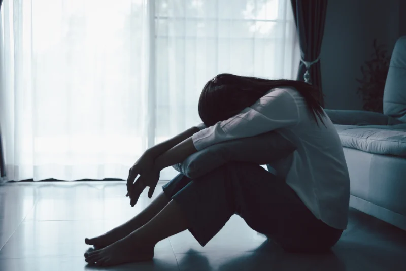 Woman sitting alone on the floor, overwhelmed by low mood