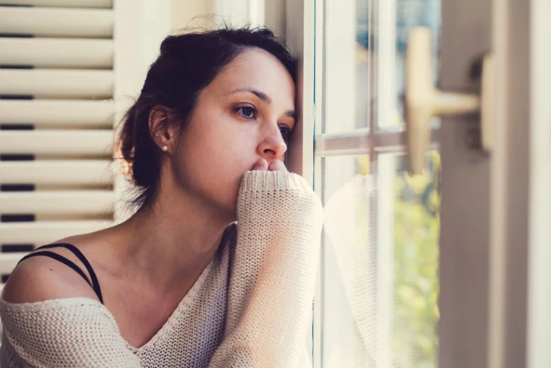 Woman staring out a window, lost in anxious thought