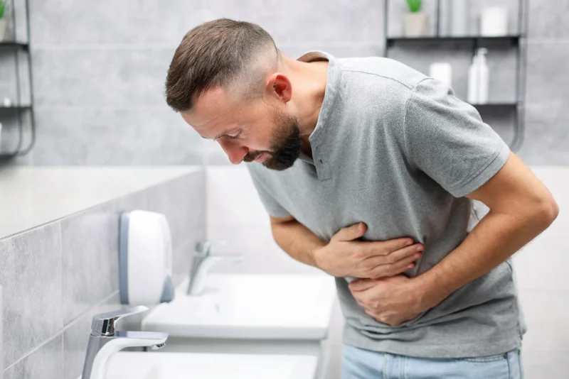 Man holding his stomach in discomfort from digestive pain