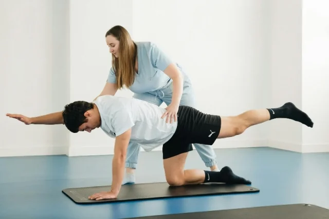 Physiotherapist guiding a patient through a clinical Pilates exercise