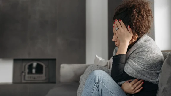 Woman sitting on a couch holding her head in exhaustion