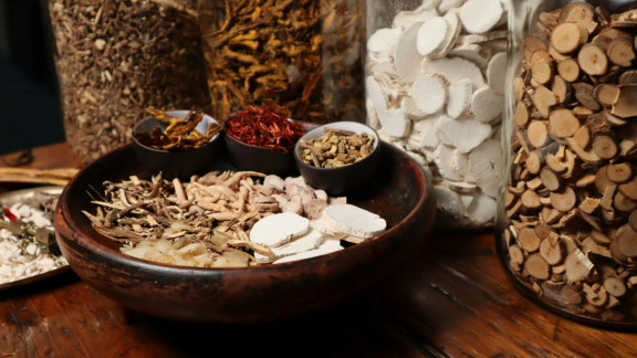 Bowl and jars of traditional Chinese herbal medicine ingredients