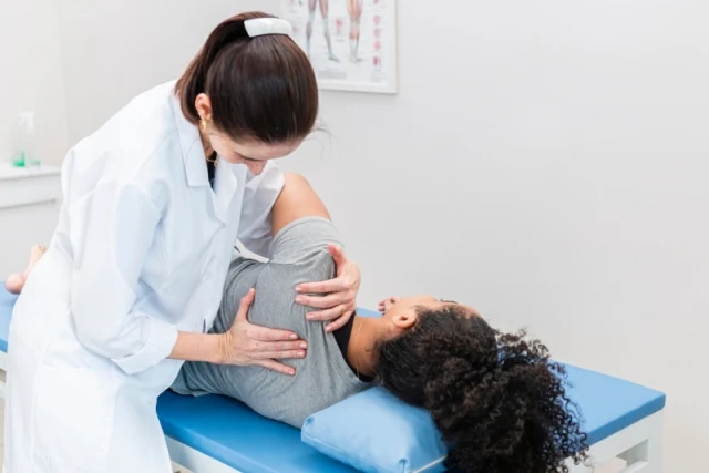 Physiotherapist assessing a patient's shoulder for a work injury