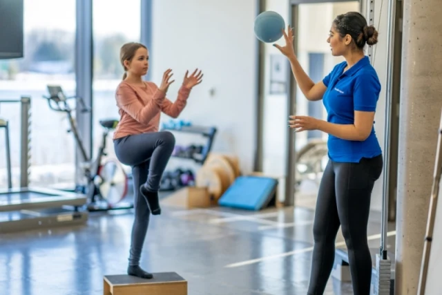 Physiotherapist guiding a client through Pilates step rehabilitation