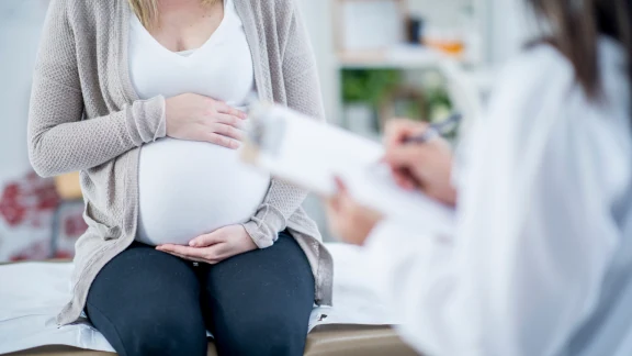 Practitioner supporting a pregnant patient's abdomen