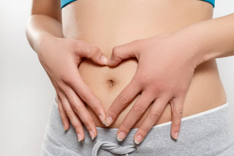 Woman holding her hands in a heart shape over her stomach